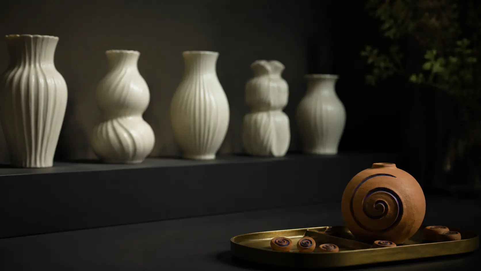 A row of identical white ceramic cups on a wooden shelf, the last cup cut open down one side